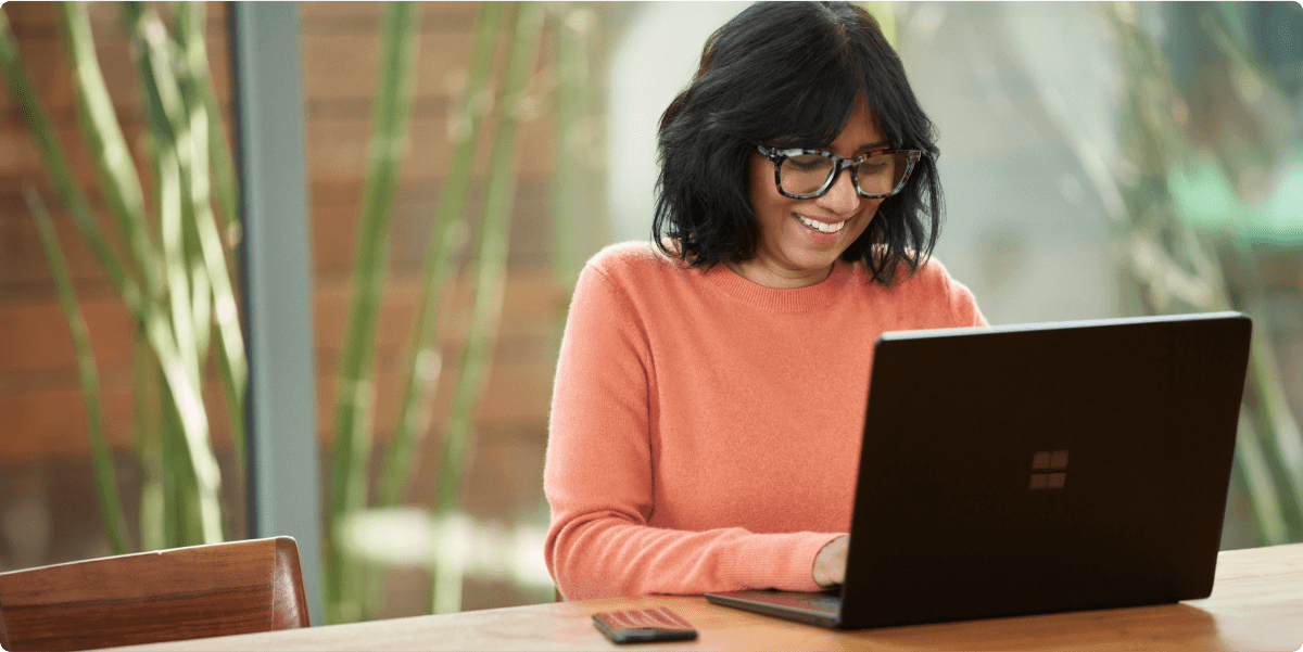 Una mujer trabajando en un entorno de oficina informal y sonriendo para sí misma.